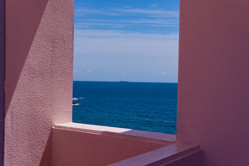 Fototapeta na wymiar この写真は壁の間から見える海と空と船の写真です。