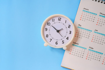 Fototapeta na wymiar analog white clock with calendar on blue paper background, flat lay, deadline concept