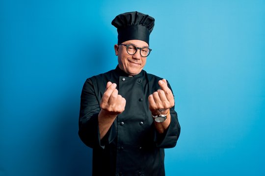 Middle Age Handsome Grey-haired Chef Man Wearing Cooker Uniform And Hat Doing Money Gesture With Hands, Asking For Salary Payment, Millionaire Business