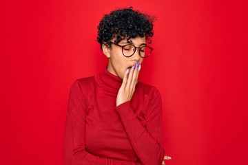 Fototapeta na wymiar Young beautiful african american afro woman wearing turtleneck sweater and glasses bored yawning tired covering mouth with hand. Restless and sleepiness.