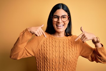 Young beautiful hispanic woman wearing glasses over yellow isolated background looking confident...