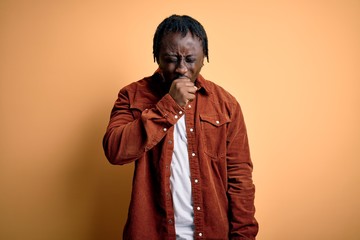 Young handsome african american man wearing casual jacket standing over yellow background feeling unwell and coughing as symptom for cold or bronchitis. Health care concept.