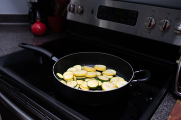 zucchini and squash circles being fried stove top on a skillet 