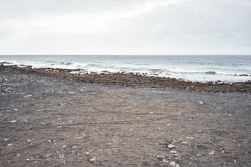 Photo of black sand beach and atlantic ocean at volcanic shore. Canary islands tourism.