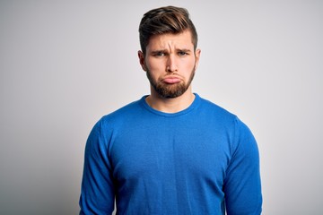Young handsome blond man with beard and blue eyes wearing casual sweater depressed and worry for distress, crying angry and afraid. Sad expression.