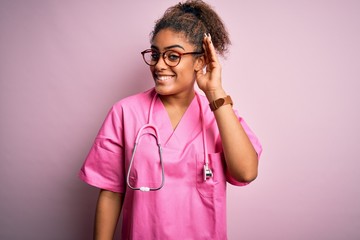 African american nurse girl wearing medical uniform and stethoscope over pink background smiling...