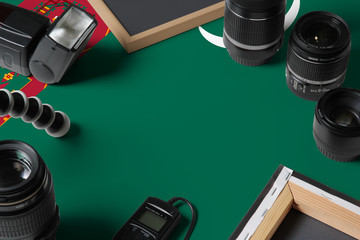 Turkmenistan national flag with top view of personal photographer equipment and tools on white...