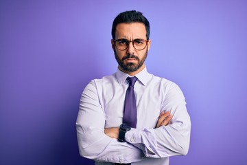 Handsome businessman with beard wearing casual tie and glasses over purple background skeptic and nervous, disapproving expression on face with crossed arms. Negative person.