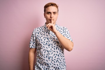 Young handsome redhead man wearing casual summer shirt standing over pink background asking to be quiet with finger on lips. Silence and secret concept.