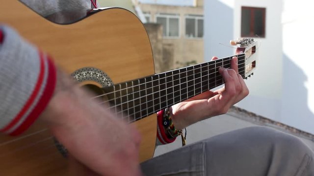Man playing acoustic guitar outdoors, close up