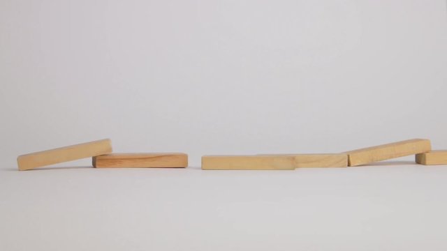 Man bumping Jenga blocks in a row for a chain reaction