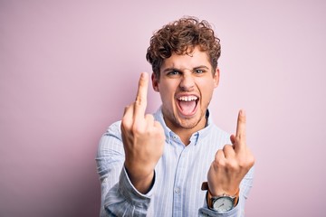 Young blond handsome man with curly hair wearing striped shirt over white background Showing middle...