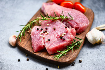Raw pork meat on wooden cutting board at kitchen table for cooking pork steak roasted or grilled with ingredients herb and spices - Fresh pork