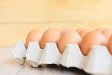 Eggs in egg box on wooden background / Close up of raw chicken eggs organic food
