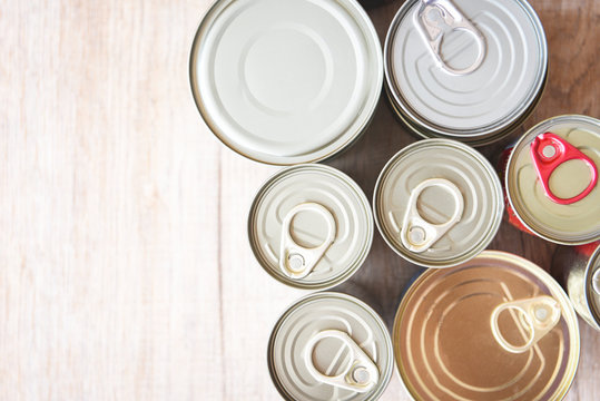 Various canned food in metal cans on wooden background , top view canned goods non perishable food storage goods in kitchen home or for donations