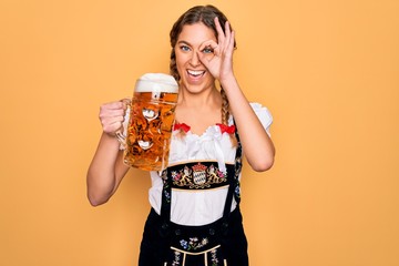 Beautiful blonde german woman with blue eyes wearing octoberfest dress drinking jar of beer with...