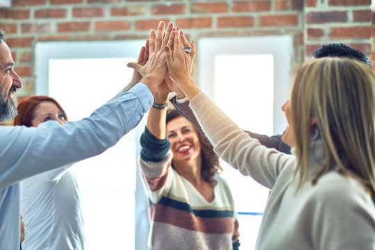 Group of business workers standing with hands together highing five at the office