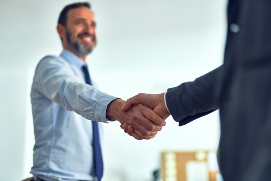Businessmen standing together shaking hands for agreement at the office