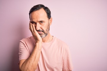 Middle age hoary man wearing casual t-shirt standing over isolated pink background thinking looking tired and bored with depression problems with crossed arms.