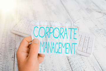 Conceptual hand writing showing Corporate Management. Concept meaning all Levels of Managerial Personnel and Excutives Man holding colorful reminder square shaped paper wood floor