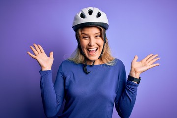 Young beautiful blonde cyclist woman wearing bike security helmet over purple background celebrating crazy and amazed for success with arms raised and open eyes screaming excited. Winner concept