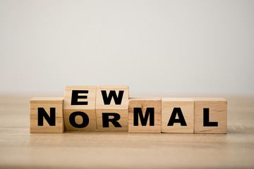 Hand flipping wooden block cubes for new normal wording. The world is changing to balance it into...