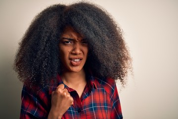 Young beautiful african american woman wearing casual shirt over isolated background angry and mad raising fist frustrated and furious while shouting with anger. Rage and aggressive concept.