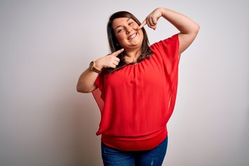 Beautiful brunette plus size woman wearing casual red t-shirt over isolated white background smiling cheerful showing and pointing with fingers teeth and mouth. Dental health concept.