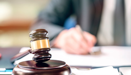 Judge wooden gavel on sounding block on the teble.