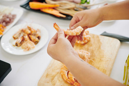 Close-up image of woman peeling boiled shrimps when making healthy salad for lunch