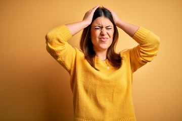 Young beautiful woman wearing casual sweater over yellow isolated background suffering from headache desperate and stressed because pain and migraine. Hands on head.