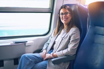 Fototapeta na wymiar Young beautiful woman smiling happy and confident. Sitting with smile on face travelling by train