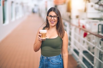 Young beautiful woman on vacation smiling happy and confident. Standing on a deck of ship with...