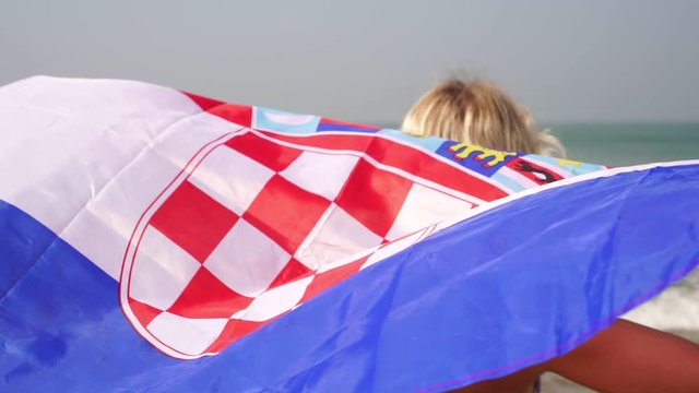 Young woman with croatian flag on the sea beach, slow motion. Tourism in Croatia - Powered by Adobe