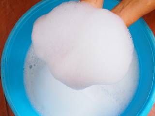 Above of bubble in hand on washing basin washing dirty clothes with hands.