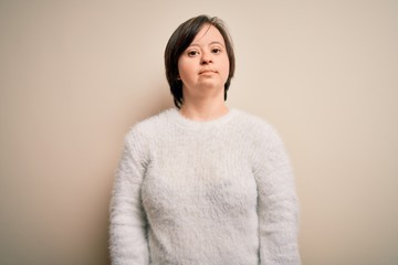 Young down syndrome woman standing over isolated background Relaxed with serious expression on face. Simple and natural looking at the camera.