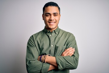 Young brazilian man wearing casual shirt standing over isolated white background happy face smiling with crossed arms looking at the camera. Positive person.