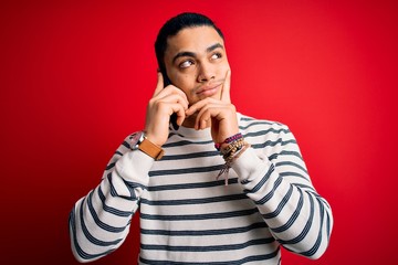 Brazilian man having conversation talking on the smartphone over isolated red background serious...