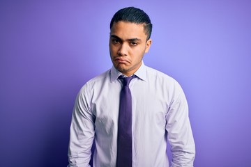 Young brazilian businessman wearing elegant tie standing over isolated purple background depressed and worry for distress, crying angry and afraid. Sad expression.
