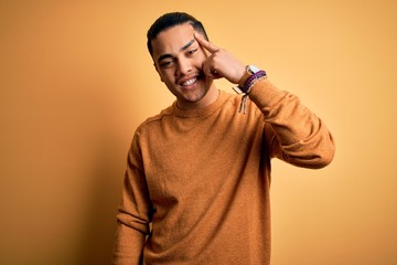 Young brazilian man wearing casual sweater standing over isolated yellow background Smiling...