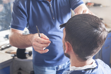 Barber making stylish haircut with in beauty salon.