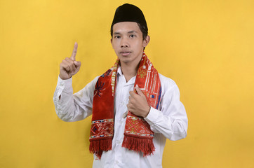 portrait of Asian Muslim man expressing being preached isolated on a yellow background
