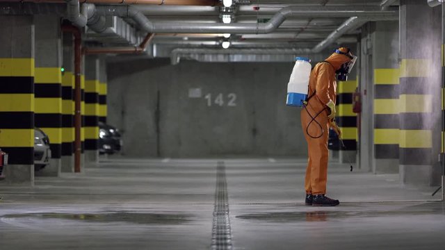 Frontline Worker In Full Hazmat Suit Disinfects Coronavirus Contaminated Car Park