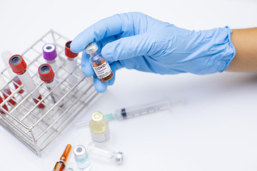 Doctor hand holding ampules and different medicine bottle on white background in the hospita.Vaccination to patient for influenza protection.Coronavirus vaccine prevention and against concept.