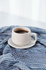 Cup of delicious black coffee on blue and white plaid tablecloth