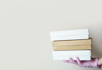 Hands in gloves hold eco food boxes for delivery on a light background. Place for text