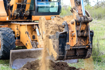 Fototapeta na wymiar The modern excavator performs excavation work on the construction site