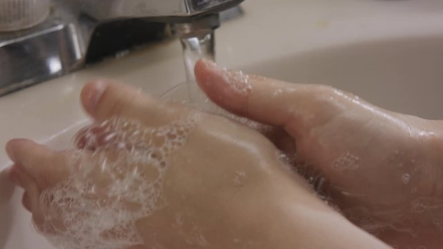 White female hands wash with soap foam and bubbles in slow motion close up shot.