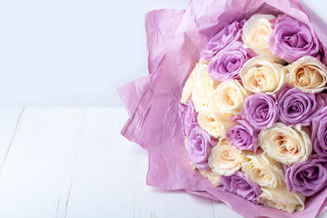 Bouquet of fresh amazing white and purple roses in craft paper on white background for postcard, cover, banner. Beautiful flowers as gift for Mother’s, Valentine’s Day, Birthday or Wedding. Copy space