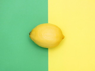 Fresh lemon is placed symmetrically on a yellow and green background